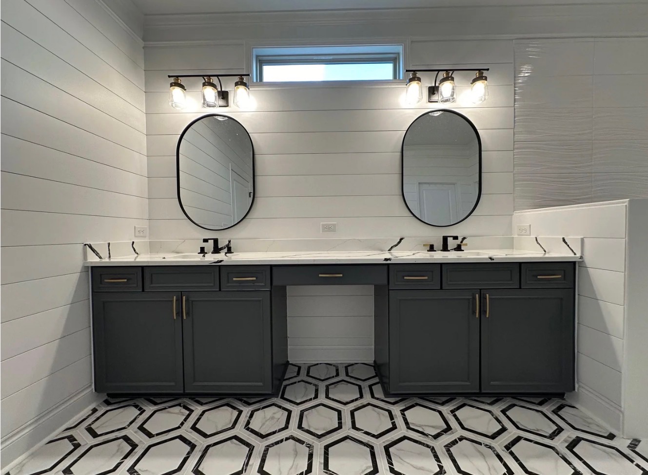 Dual vanity with marble countertops and shiplap walls