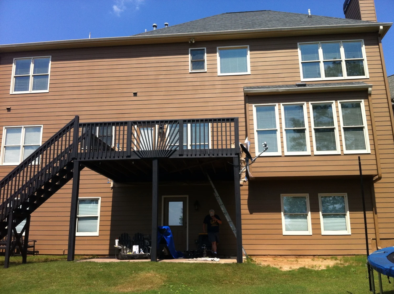 Elevated dark-stained deck with staircase on two-story home